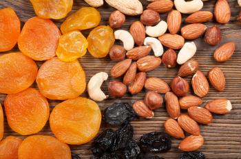 Different dried fruits and nuts on a wooden background. Apricots, almonds and hazelnuts