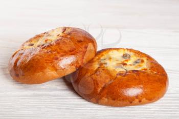 Two fresh homemade buns with cottage cheese and raisins on a wooden background