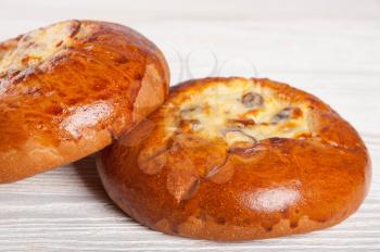 Two fresh homemade buns with cottage cheese and raisins on a wooden background
