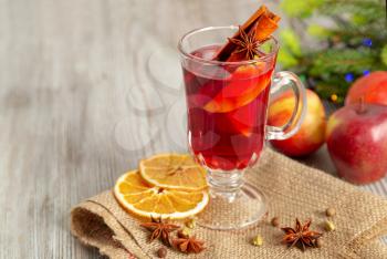 Mulled wine with spices and fruit on a wooden table. Traditional Christmas hot drink with red wine, apples, oranges and cinnamon