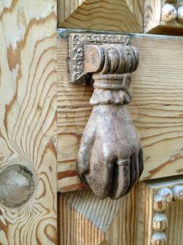 Old bronze knocker on a wooden door full of details