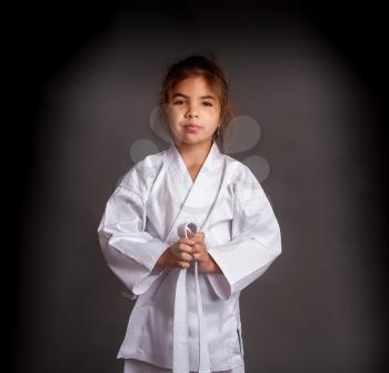 Little girl karatek in a kimono tie a white belt getting ready for training