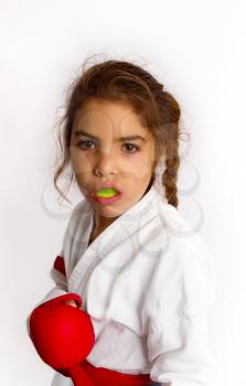 A little girl karateka in white kimono and in a red belt with a mouth guard in her lips should be ready for the fight