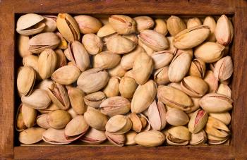 background from salty roasted pistachios in a wooden square bowl