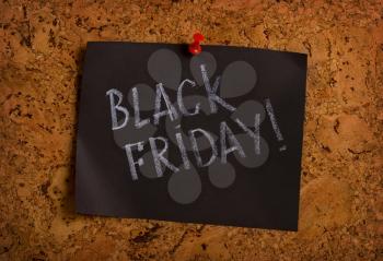 Handwritten black Friday on a sheet of paper pinned with a button to the wall of a cork tree