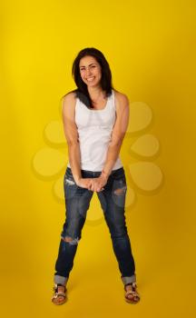 Pretty girl with dark hair in casual clothes in a good mood is standing on a bright yellow background