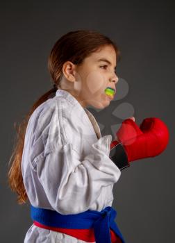 karate girl in kimono and red gloves for the fight with a protective mouthguard for a dark background