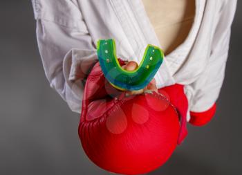 Children's hand in a red sports glove holds a protective cap for martial arts