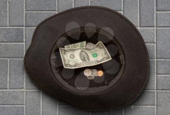 a fairly well-worn felt hat of a homeless man in which he collects small money and coins