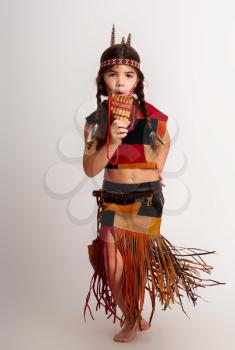 little indian girl in traditional dress plays the flute