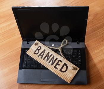 turned off laptop with a wooden sign that says banned