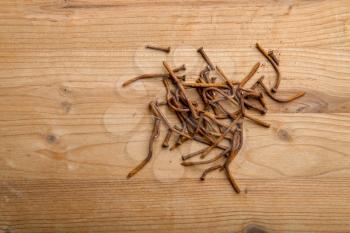 a lot of old rusty bent nails lying on a wooden board