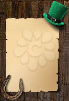 Poster for St. Patrick's Day empty sheet of paper, green leprechaun hat and horseshoe on an old wooden background