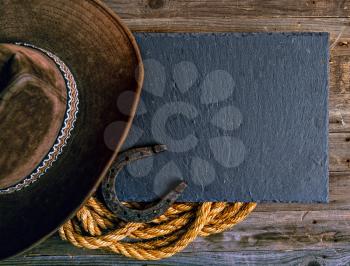 Black chalk board lasso horseshoe and traditional cowboy hat on wooden background