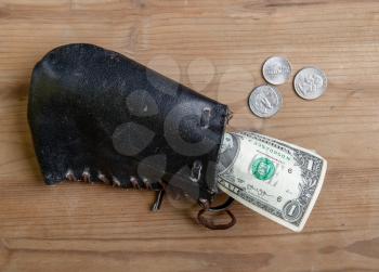 several modern dollar bills in an old leather medieval wallet