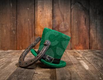 A classic green hat is a fairytale leprechaun hat and a metal horseshoe that brings good luck. Symbols of St. Patrick's Day on a wooden table in a Pub