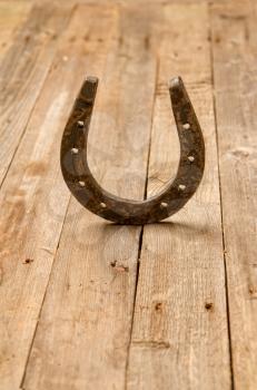 Steel horse horseshoe standing upright with its horns up on an old wooden table