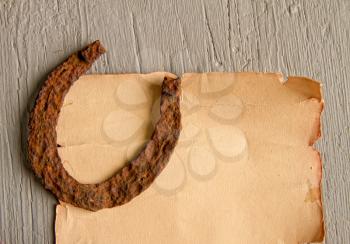 A very old rusty horse horseshoe a symbol of good luck lies on an empty paper scroll