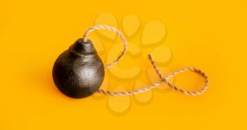 classic round black antique bomb with a long non-burning rope wick on a yellow background