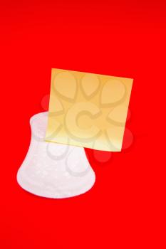 White feminine sanitary pad with empty yellow paper for text on a bright red background