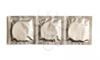 ribbon of three condoms in sealed silver packaging without text isolated on white background