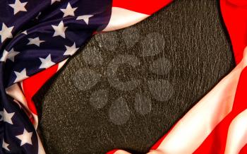 Flag of the United States of America lying on a dark textured stone surface to form a frame for text