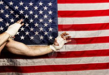 Strong male hands of an MMA fighter wrapped in protective bandages against the background of the USA flag