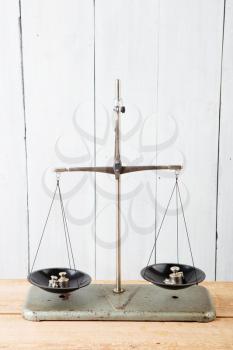 Balance scales on the white wooden background