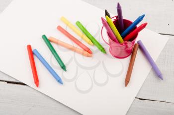 colorful crayons and blank paper on the wooden desk