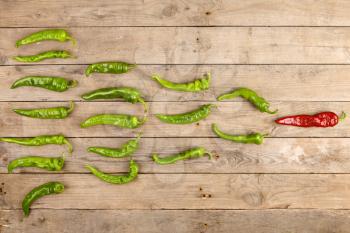 Leadership concept - red hot chili pepper leading the group of green peppers