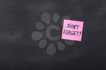 Don't forget inscription on colorful stickers on blackboard