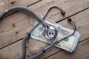 health insurance concept - stethoscope over the money on the table