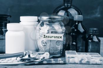 Saving money for health care insurance - money glass, stethoscope, pills and bottles