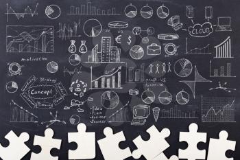 Business concept - jigsaw, sketch with schemes and graphs on chalkboard