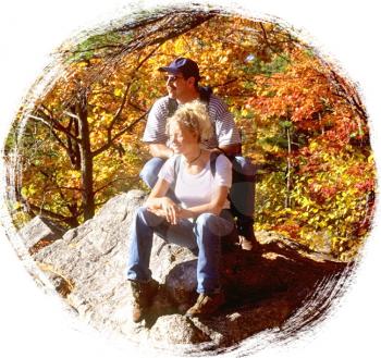 Royalty Free Photo of a Couple Sitting on a Rock in the Autumn Forest