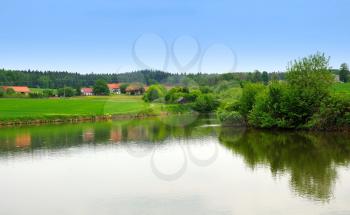 Outdoor photo of view on the green field and small pond.