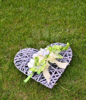 Decoration heart with green flower and ribbon in the grass.