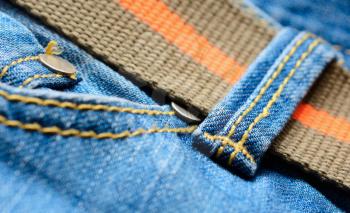 Blue jeans with orange belt, macro shot.