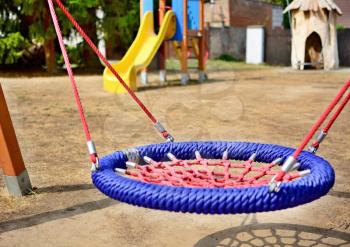 Close-up of colorful blue-red nest swing seat in the playground.