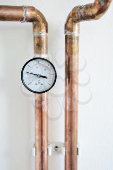 Closeup of pressure gauge connected to copper heating pipe.