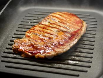 Fresh Grilled Beef Steak in Steam and Smoke on the Iron Grill Pan.