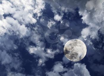 Full moon in midnight deep blue sky with clouds.
