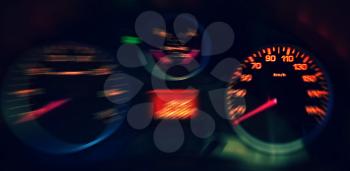 A Close up View of the Blurred Red Illuminated Speedometer in the Car.