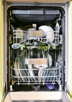 Front view into opened dishwasher full loaded of dishes. Full frame background shot.