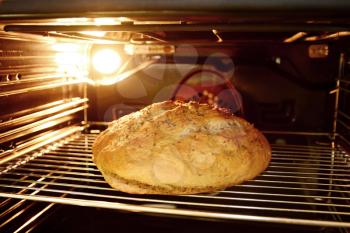 Baking homemade bread in oven. Looking into oven during baking of loaf of bread on metal grate.