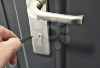 A hand holding a key for inserting a key into the door lock. Unlocking the security lock.
