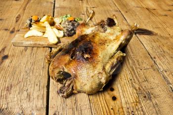 Roasted Duck With Potatoes, Carrots and Stuffing Resting On A Wooden Table