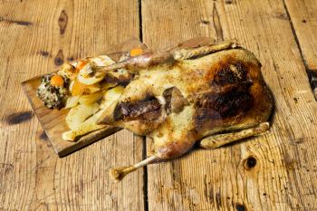 Roasted Duck With Potatoes, Carrots and Stuffing Resting On A Wooden Table