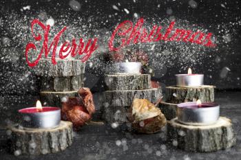 Merry Christmas. Christmas candles burning, decoration on wooden logs resting on rustic wooden background with Snow Flakes And Stardust