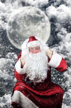 Santa Claus in the Christmas Night , with Sky full of Stars, Snow, Clouds and The Moon in the Background